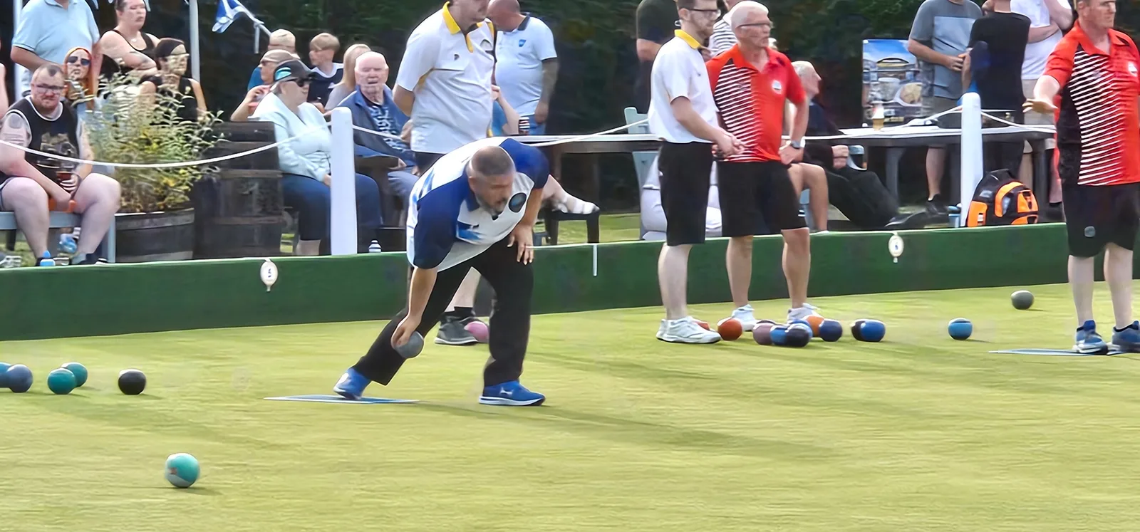 A dynamic shot of James "Basher" Brown in his Polmaise kit, fully focused on his delivery during the Gents Pairs final