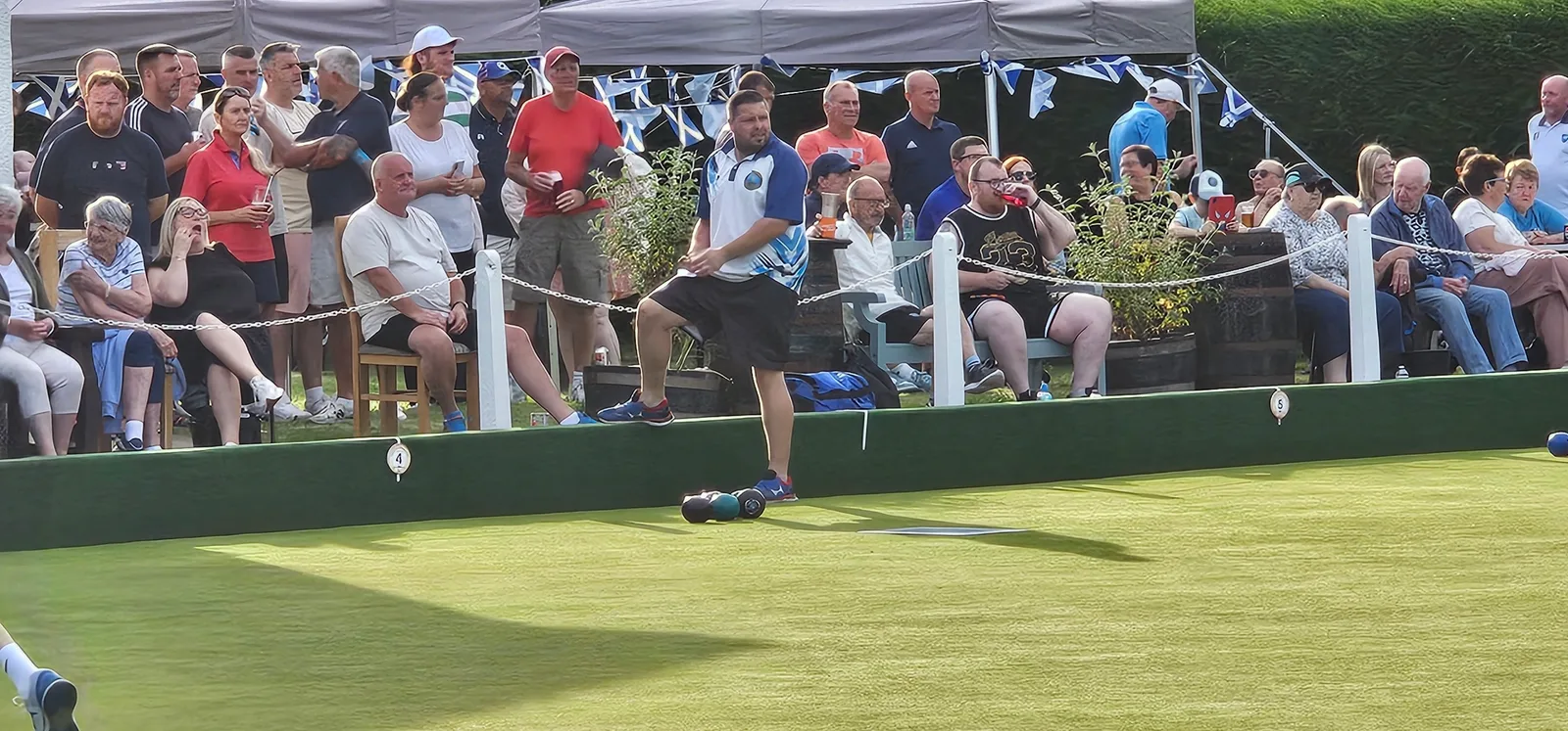 Gary Malcomson stepping up to the mat during the fiercely contested Gents Pairs match, surrounded by watching supporters